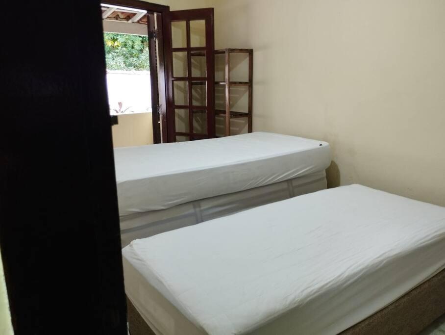 Zimmer mit 3 Betten und einem Fenster in der Unterkunft Ap Aconchegante - 4 pessoas in Bertioga