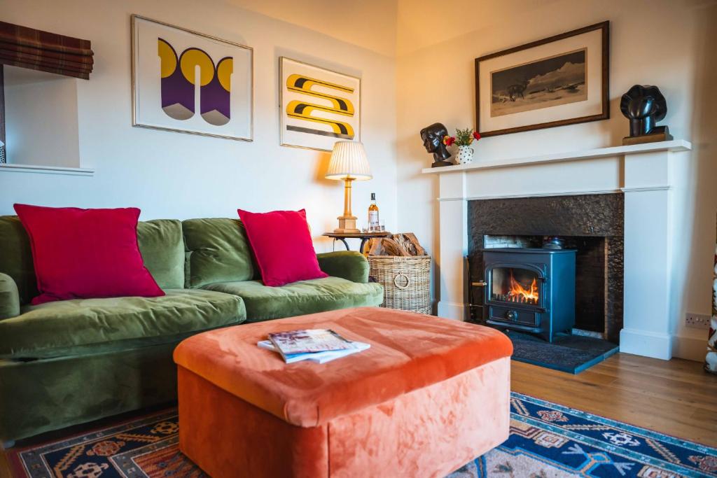 a living room with a green couch and a fireplace at Kinkell Cottage in Dingwall