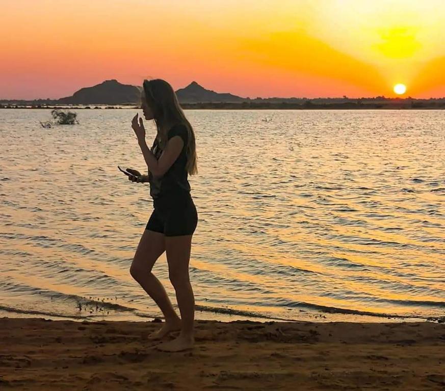 a woman standing on the beach at sunset at Safari Abu Simbel in Abu Simbel