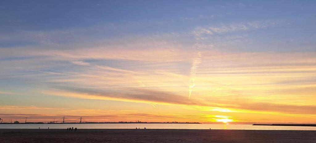 una puesta de sol en la playa con el sol en el cielo en Ático primera línea de playa con vistas al mar-Climatizado-Wifi-Parking en El Puerto de Santa María