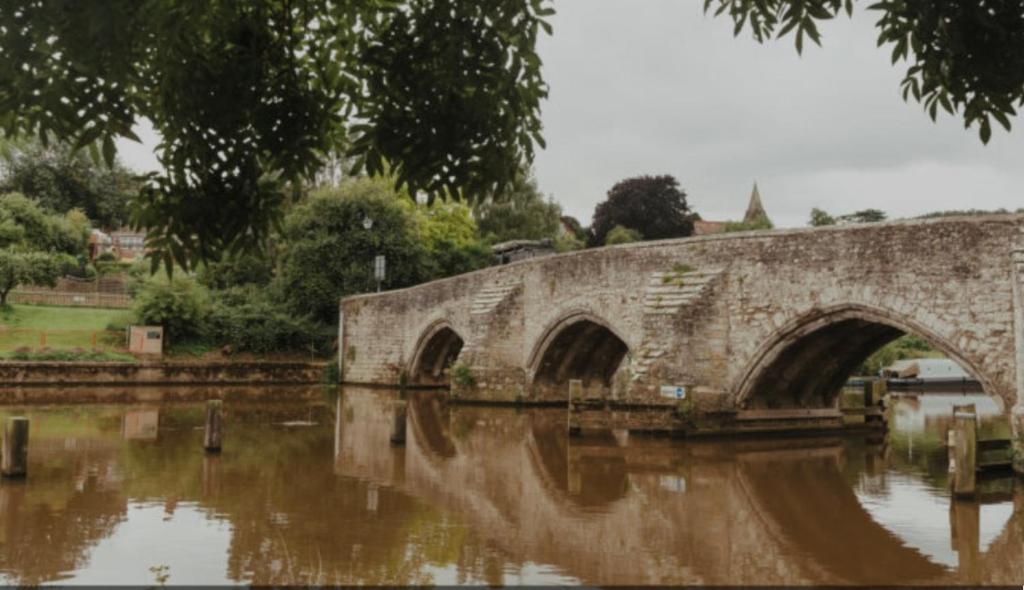 un vieux pont en pierre sur une étendue d'eau dans l'établissement Guest house in East Farleigh, à East Farleigh