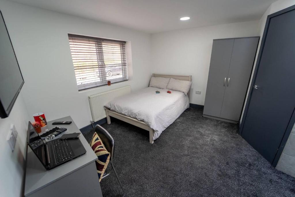 a bedroom with a bed and a desk with a laptop at Captivating 1-Bed studio in Birmingham in Birmingham