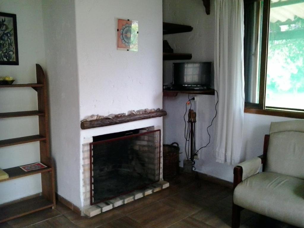 a living room with a fireplace and a chair at ANAHATA in Barra del Chuy