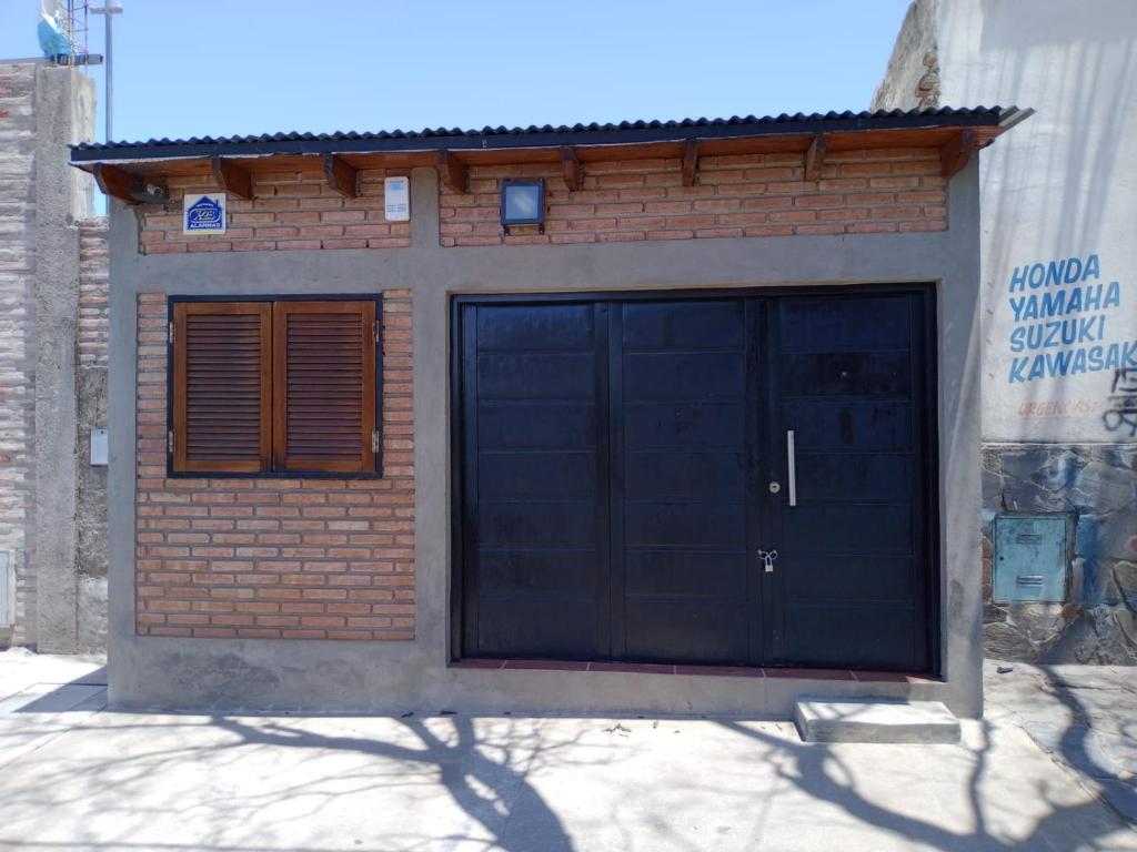 een garage met een zwarte deur en een bakstenen gebouw bij El Refugio in San Fernando del Valle de Catamarca