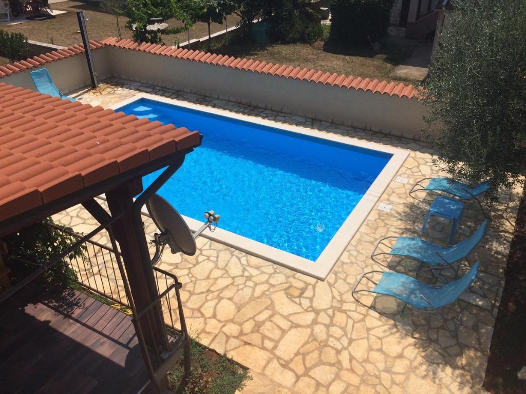a swimming pool with two chairs and a table at Fabris Apartments with pool and top location near sea in Novigrad Istria