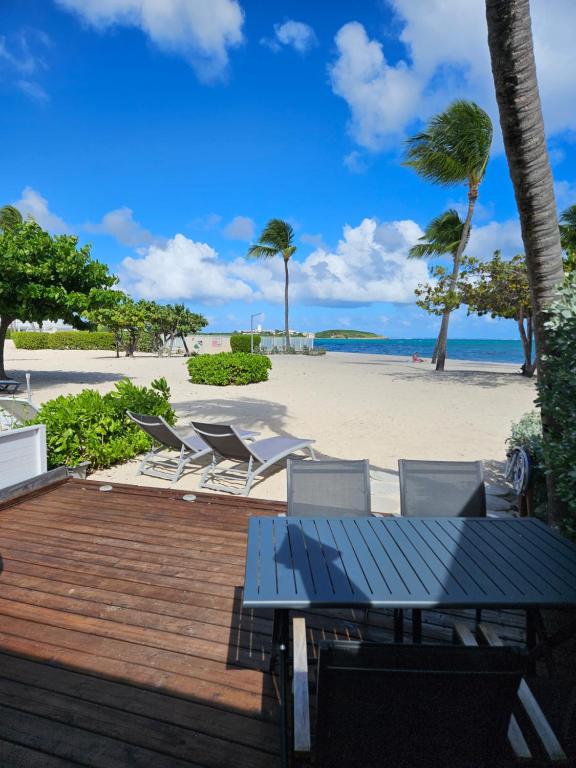 una terraza con mesa y sillas y la playa en Tekila Beach, appt-condo au bord de mer a Baie Nettle, Saint-Martin SXM, en Saint Martin