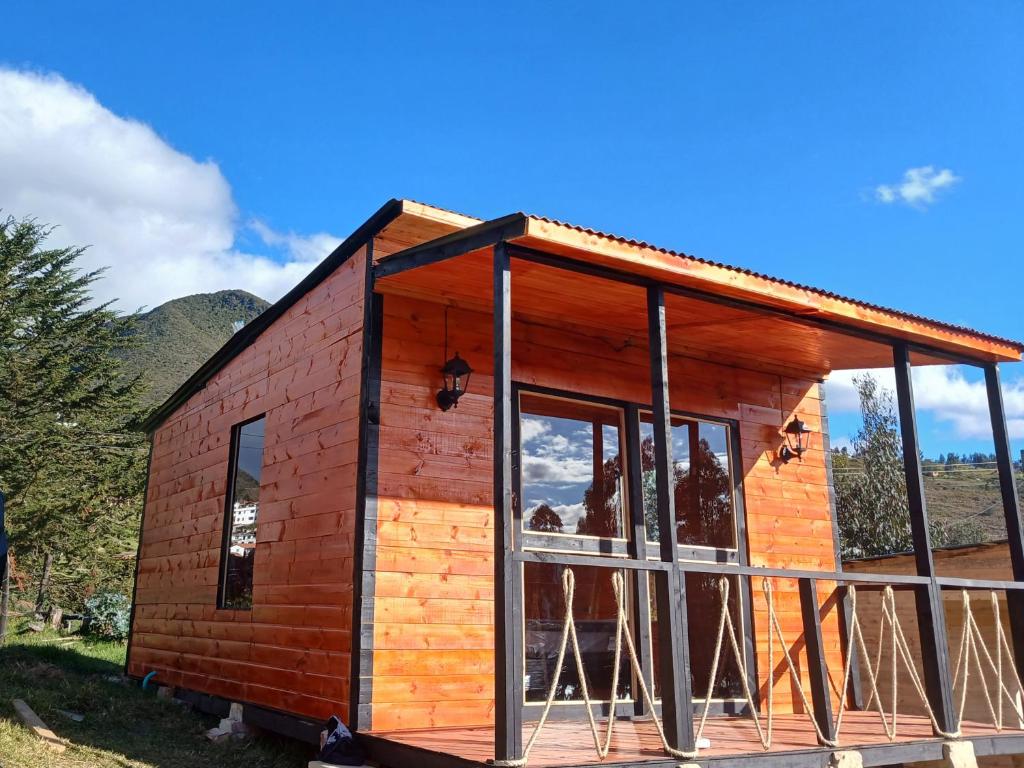 Cabaña de madera pequeña con ventana grande en Hospedaje cabaña Guatavita Finca las Acacias, en Guatavita