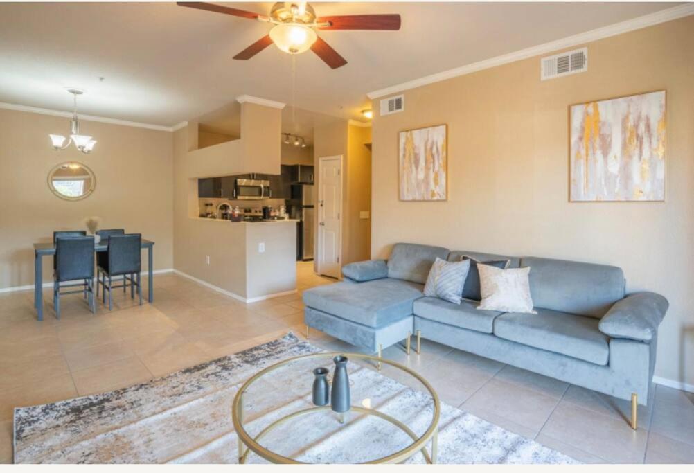 a living room with a blue couch and a ceiling fan at Modern 2BR-2BA Condo Pool, Gym & Parking Near Airport in Phoenix