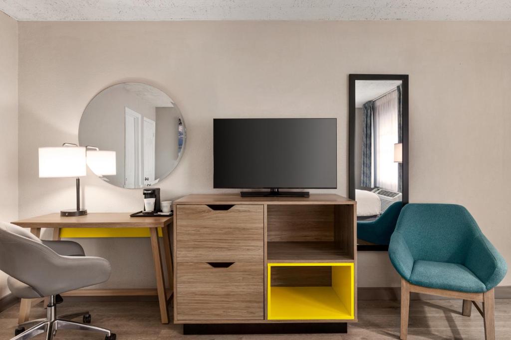 a room with a tv and a chair and a mirror at Days Inn by Wyndham Miami Airport North in Miami