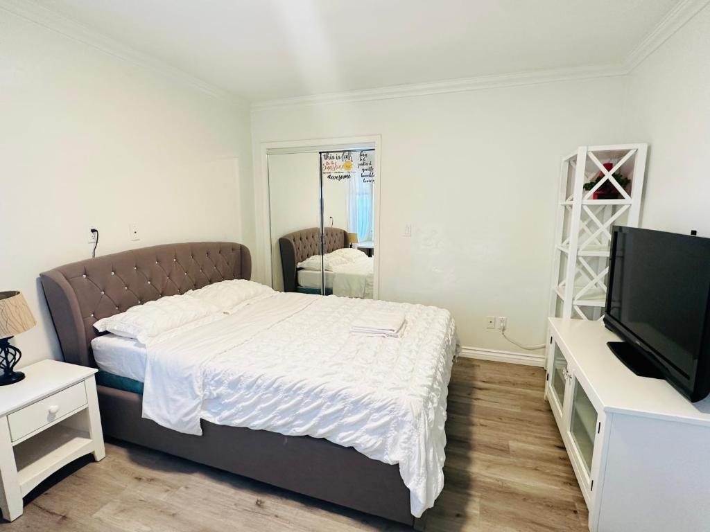 1 dormitorio con 1 cama, TV y espejo en Nice bedroom shared bath free parking, en West Covina