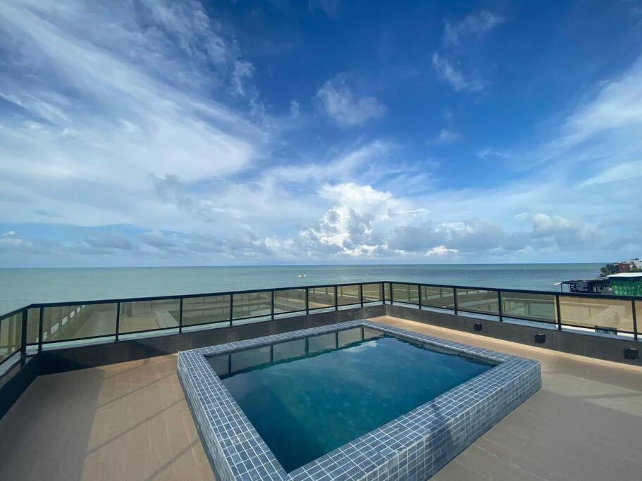 a swimming pool with the ocean in the background at Flat Santorini, beira-mar 206 in João Pessoa