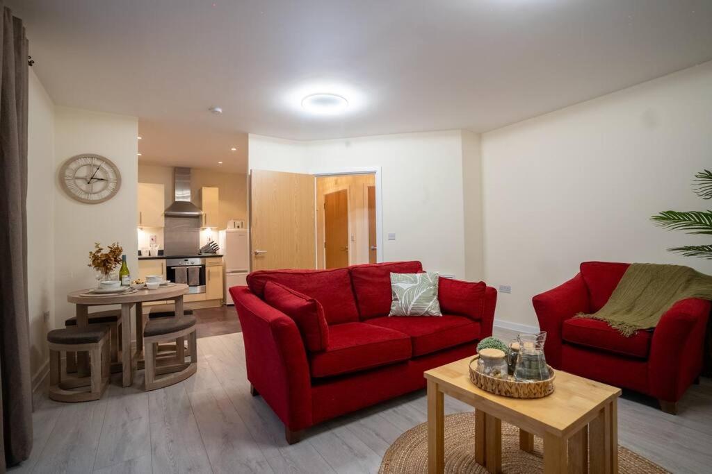 a living room with two red couches and a kitchen at Cosy 2 Bedroom flat in Stevenage in Stevenage