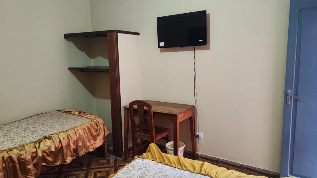 a room with a bed and a desk and a tv at The House Tarija in Tarija