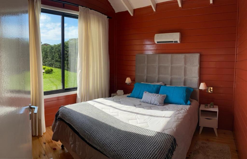 um quarto com uma cama com almofadas azuis e uma janela em Recanto do Noah em Painel