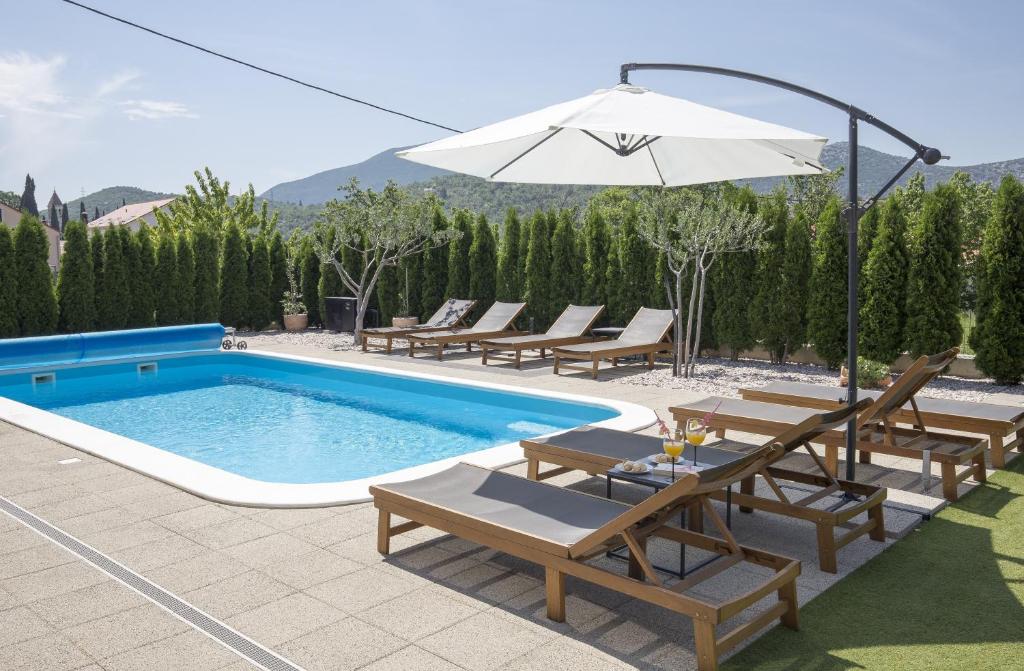 a swimming pool with chairs and an umbrella at Holiday Home EB with Heated Pool in Gata