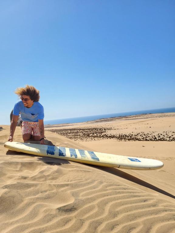 Ein kleiner Junge, der auf einem Surfbrett am Strand sitzt. in der Unterkunft Surf Break Morocco in Imsouane