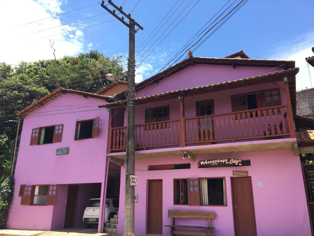 una casa rosa con balcón en la parte superior en Aconchego do céu, en Conceição da Ibitipoca