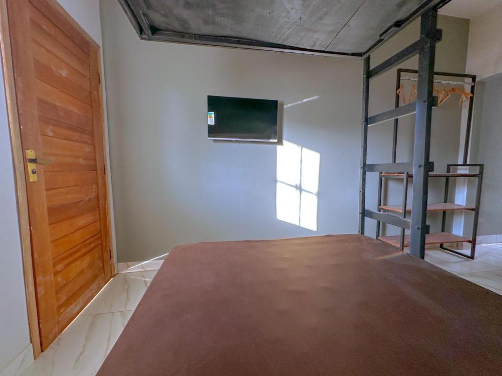 Cette chambre comprend un lit et une porte en bois. dans l'établissement Casa Loft para temporada Guarapari, à Guarapari