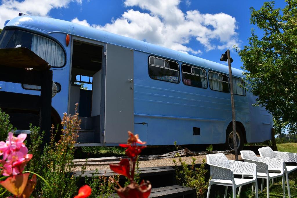un autobús azul estacionado con sillas en un campo en Evi the school bus at Oromahoe Downs Farm, en Puketona
