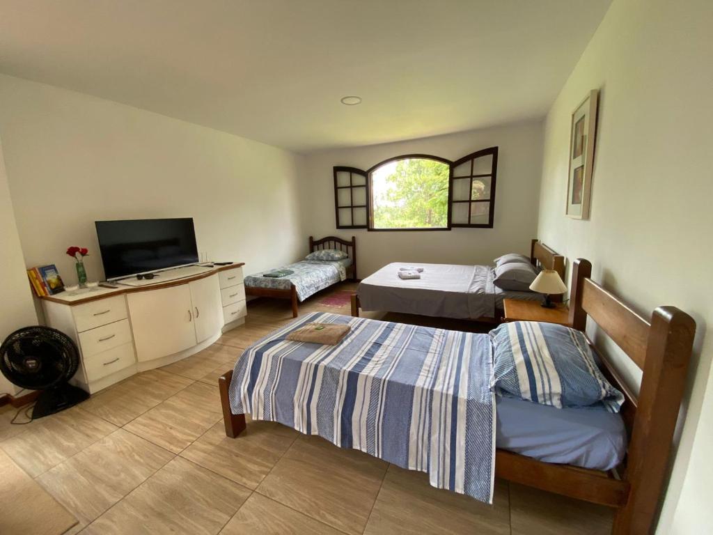 um quarto com 2 camas e uma televisão de ecrã plano em Recanto da Paz, Miguel Pereira RJ em Miguel Pereira