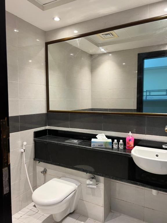 a bathroom with a toilet and a sink and a mirror at Sky Inn Hostel For Males in Dubai