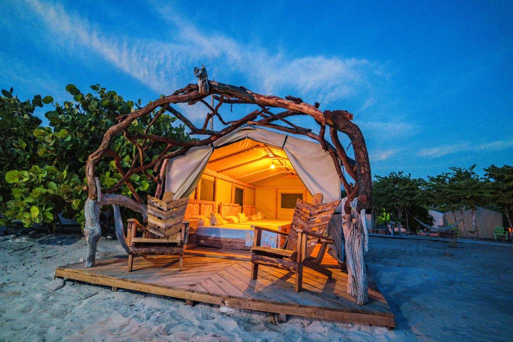 a room with a bed and two chairs on the beach at Glamping EcoLodge Cueva De Las Aguilas in Pedernales