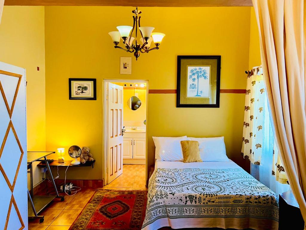 a bedroom with a bed and a yellow wall at RNM The Clubhouse, Grenada in Mount Nesbit