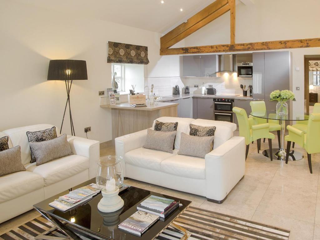 a living room with two white couches and a kitchen at Howgills Barn in Middleton