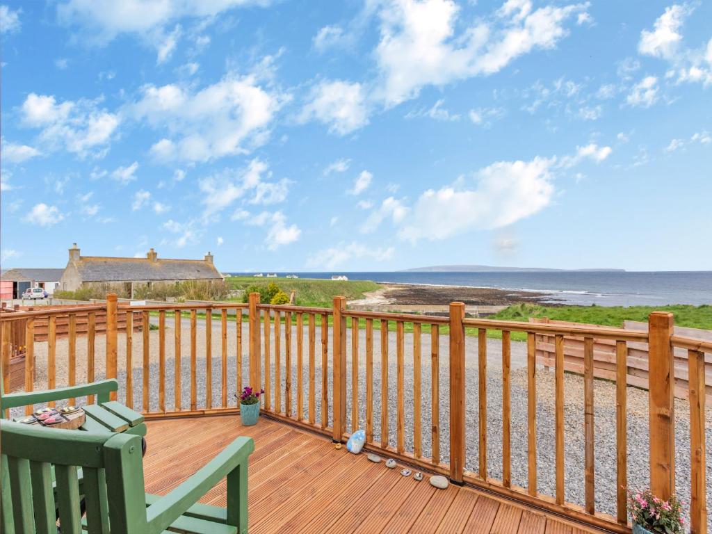 a wooden deck with a chair and a view of the ocean at Burray in Mey