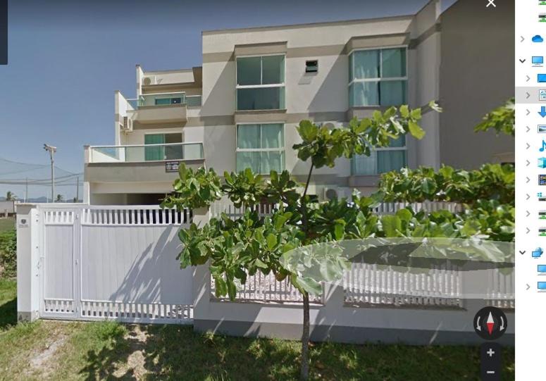a building with a white fence and trees in front of it at Pousada Souza & Souza in Barra Velha