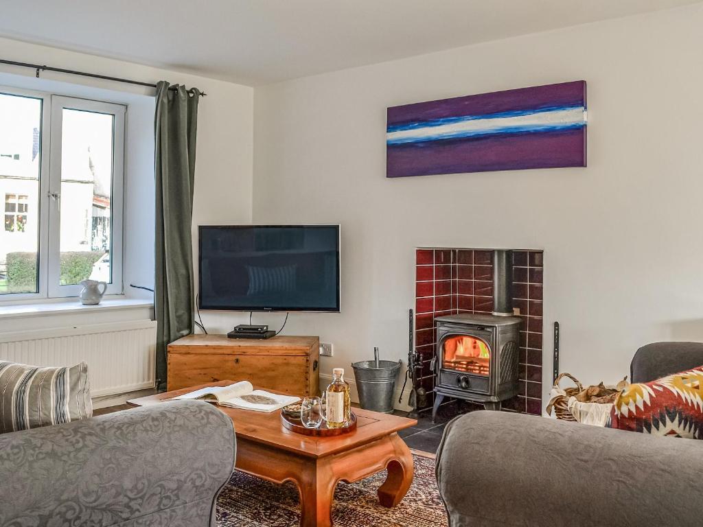 a living room with a tv and a fire place at The Cottage in Leitholm