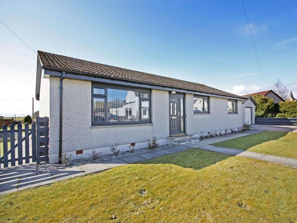 a white house with a fence in a yard at Raasay in Dornoch