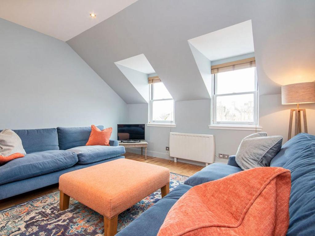 a living room with a blue couch and an orange stool at Argyle Place in Dornoch