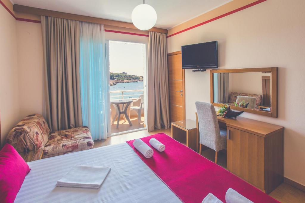 a hotel room with a bed and a table and a mirror at Apartments Deus in Dobra Voda