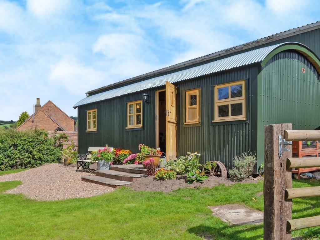 a green tiny house in a yard at Shepherds Lodge-ukc2358 in Buildwas