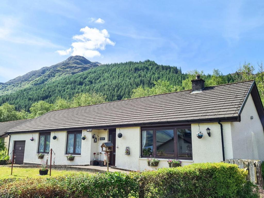 a white house with a mountain in the background at Tighur in Kintail