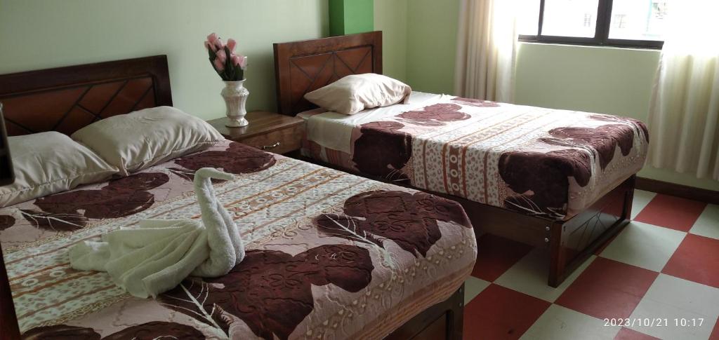 a bedroom with two beds and a vase with flowers at HOSTAL ETERNA PRIMAVERA in Copacabana