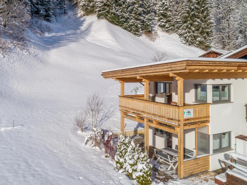 une maison en bois dans la neige recouverte de neige dans l'établissement Blick auf den Rettenstein Top 1, à Kirchberg in Tirol