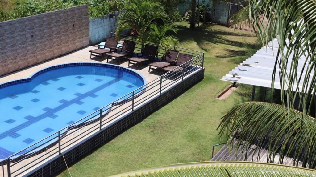 einen Pool in einem Garten mit zwei Stühlen in der Unterkunft Pousada e Hostel clubhouse in Camassari