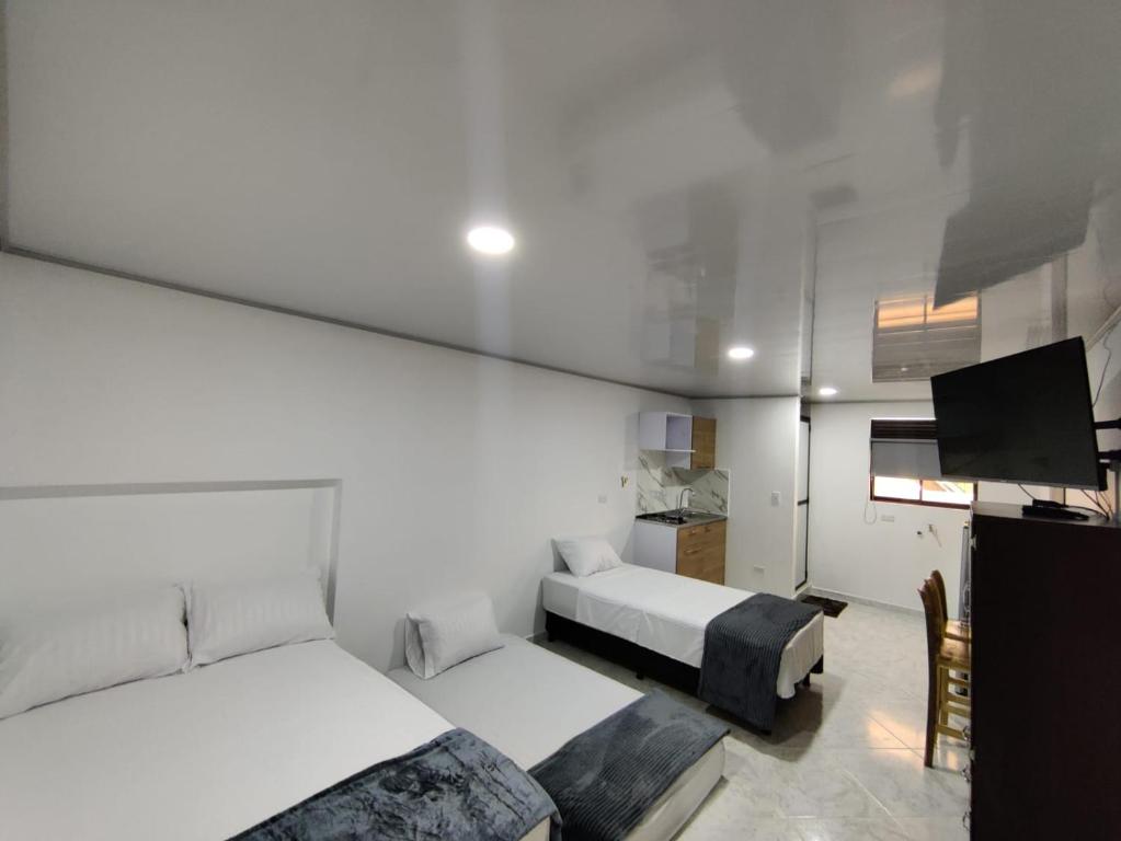 a bedroom with two beds and a flat screen tv at Apartahotel Sevilla in Medellín