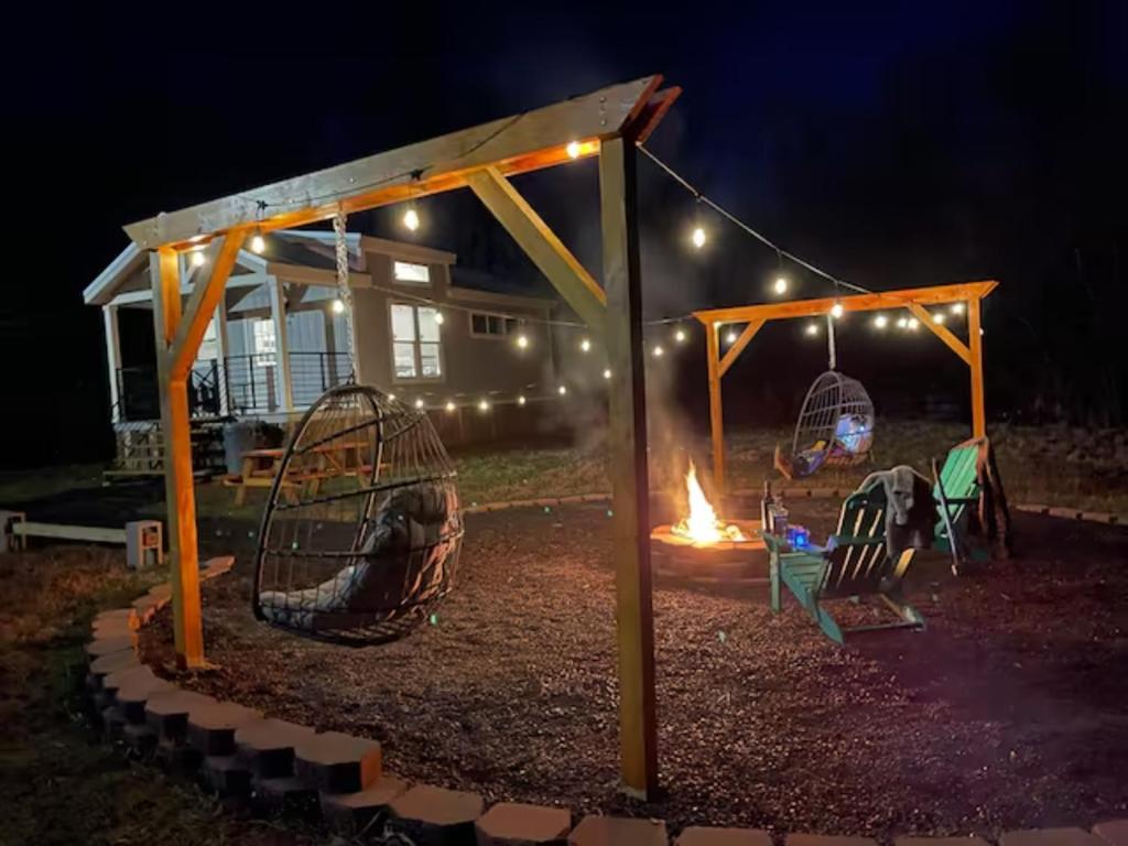 un parque infantil con columpios y chimenea por la noche en Charming New 1-BA/1-BR Home on an 60 Acre Property (Sleeps Up To 4), en Sardis