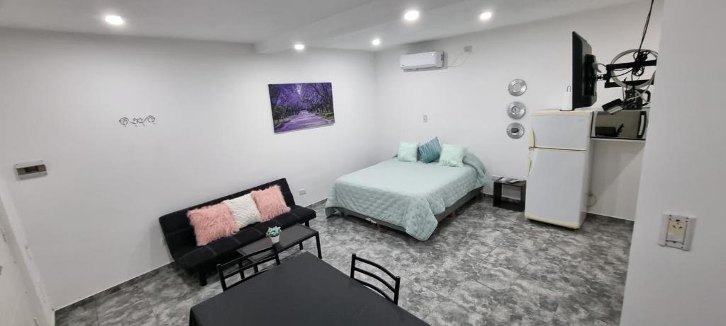 Habitación pequeña con cama y nevera. en El jacaranda Alojamiento Diario en San Luis