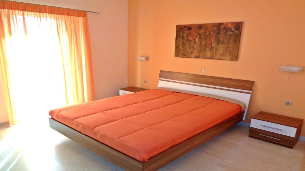 a bedroom with a bed with an orange bedspread at Villa Maria in Parga