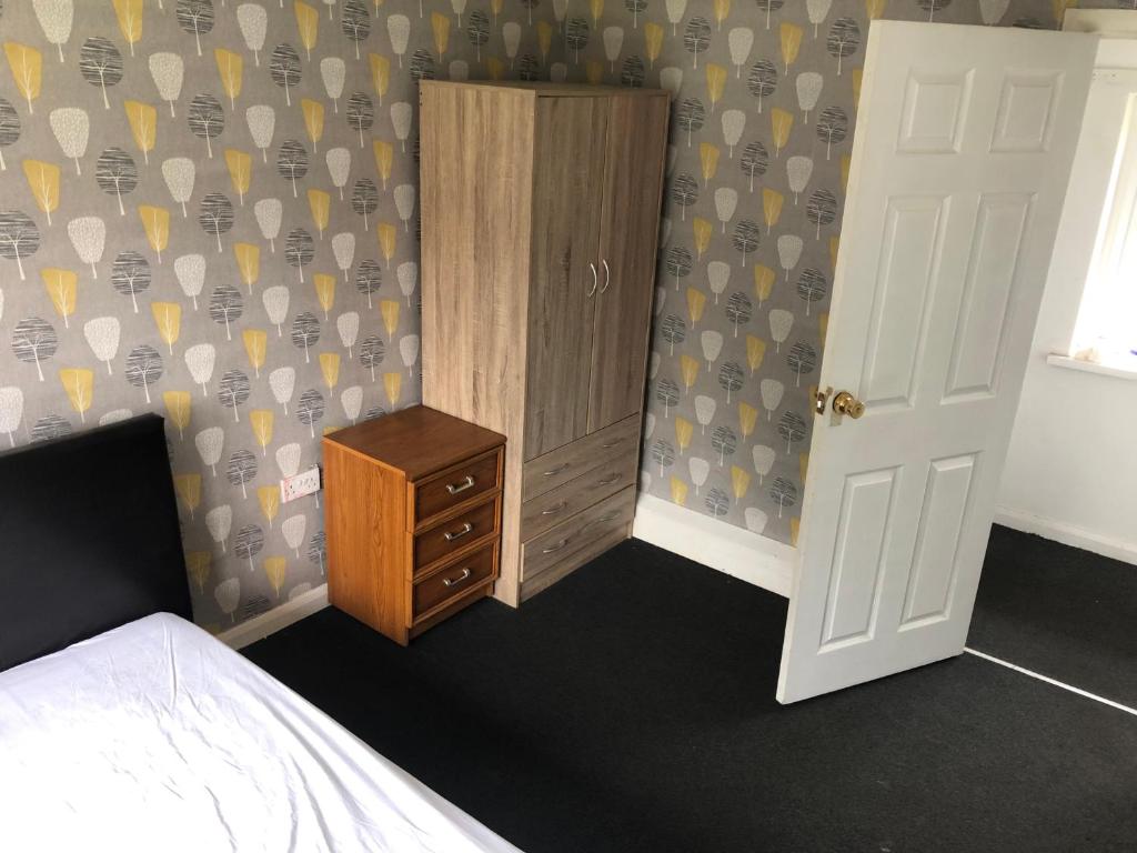 a bedroom with a bed and a dresser next to a door at Comfort zone accommodation near care home in Coseley