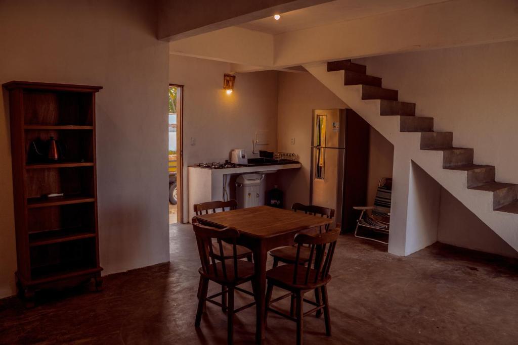a kitchen and dining room with a table and a staircase at Chalé Galo Preto in Galinhos
