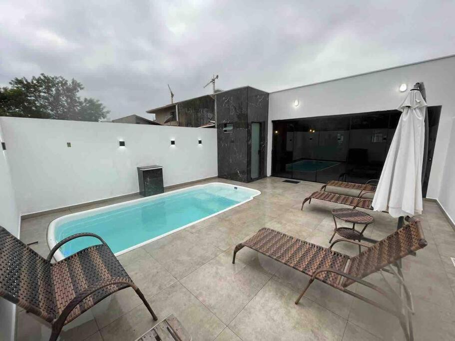 a swimming pool with two chairs and a table at Casa de praia em Penha in Penha