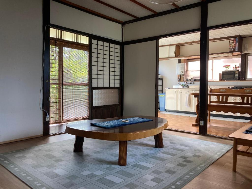 a living room with a table and a kitchen at 古民家のお宿ふうす in Amami