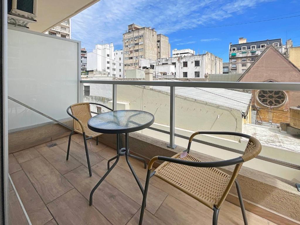 balcón con 2 sillas, mesa y ventana en San Telmo Oasis Contemporary Luxury Studios with Pool, Security, and More en Buenos Aires