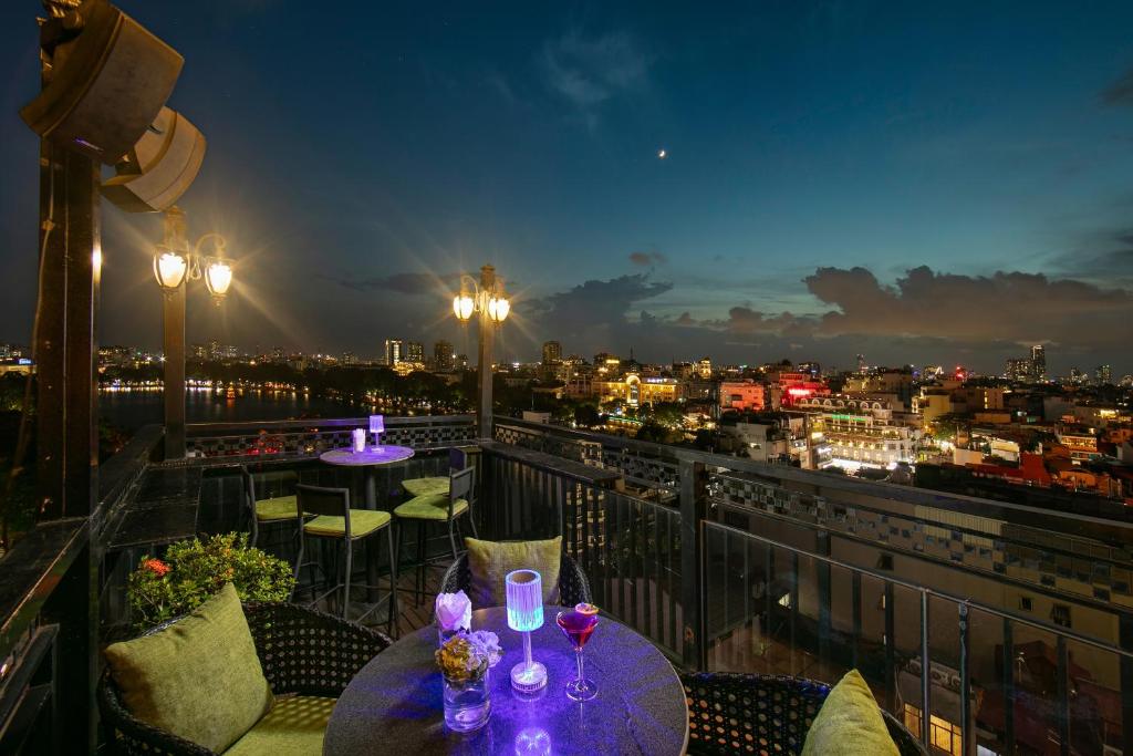 einen Balkon mit einem Tisch und Weingläsern darauf in der Unterkunft TrangTrang Premium Hotel & Sky Bar in Hanoi