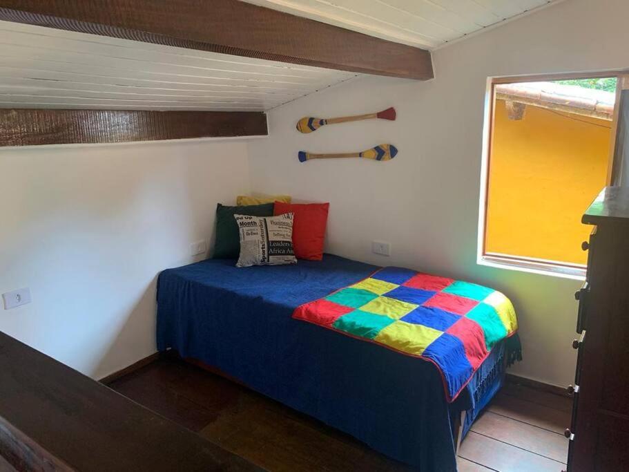 małą sypialnię z kolorowym łóżkiem w pokoju w obiekcie Chalé Praia de Boiçucanga w mieście Boiçucanga